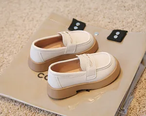 Détail de mocassins crème pour enfants avec semelle épaisse marron de style britannique.
