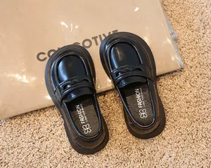 Vue détaillée de mocassins noirs classiques pour enfants de style anglais sur un tapis