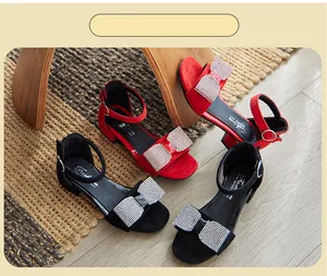 Esposizione di eleganti sandali per bambina con fiocco di strass in rosso e nero.