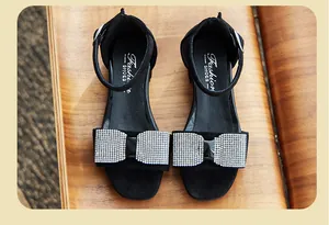 Vista dettagliata di sandali alla moda neri per bambina con fiocco di strass lucido