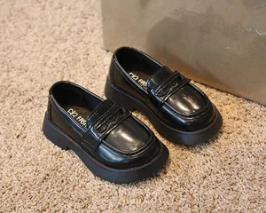 Détail en gros plan des mocassins en cuir noir à bout rond pour enfants de style britannique