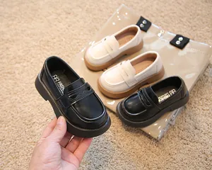 Vue détaillée de mocassins de style britannique pour enfants en noir et blanc sur tapis
