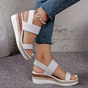 Zijaanzicht van witte wedge sandalen met elastische bandjes en gevlochten jute details.
