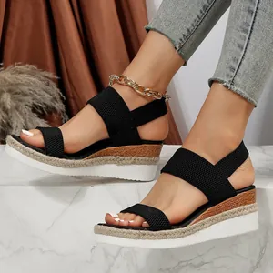 Detailweergave van zwarte sleehaksandalen met elastische banden en espadrille-platform