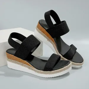 Gedetailleerd zijaanzicht van zwarte platform sandalen met elastische bandjes en vlechtzool