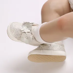 Vue détaillée de chaussures pour bébé crème avec tissu pailleté et appliqués floraux.