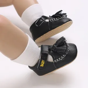 Detailansicht der schwarzen Baby-Sandalen aus Kunstleder mit Quasten und weißen Ziernähten