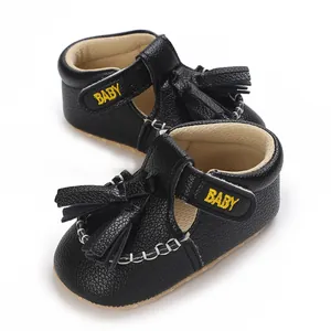 Detailansicht der schwarzen Baby-Quastensandalen mit BABY-Stickerei auf dem Riemen