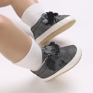Gros plan détaillé de baskets étincelantes pour bébé avec semelle souple et fleurs.