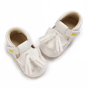 Detailansicht weißer Leder-Babyschuhe für Kleinkinder mit Quasten und Stickerei.