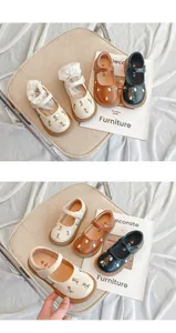 Detaillierte Nahaufnahme von Mädchen-Mary-Janes mit Blumenstickerei in Creme und Braun