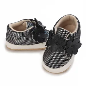 Vue rapprochée de baskets bébé pailletées noires avec ornements floraux sur le devant