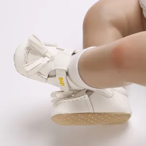 Nahaufnahme von weißen Baby-Quastensandalen mit weicher rutschfester Sohle und Bestickung.