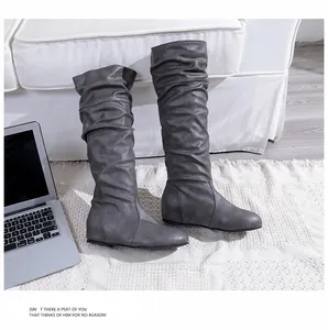 Vue détaillée de bottes froncées grises pour femmes sur un tapis blanc texturé