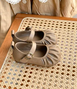 Gros plan de chaussures vintage en cuir beige pour bébé fille avec bout plissé et boucle