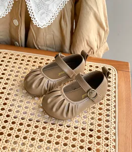Détail de chaussures bébé Mary Jane en cuir marron avec design froncé sur rotin tressé