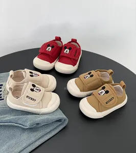 Tre paia di scarpe in tela colorate per neonati con motivo Topolino su un tavolo nero