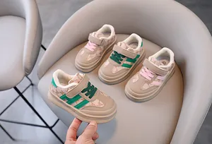 Détail de baskets pour tout-petits avec design à trois bandes et motifs d'ours sur chaise.