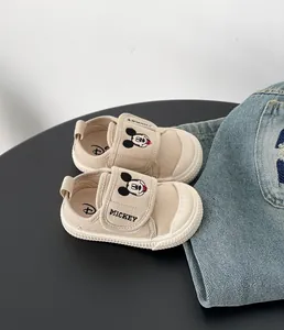 Dettaglio delle scarpine in tela beige per neonato con ricamo Topolino sulla chiusura