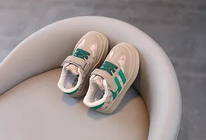 Vue détaillée de chaussures de marche beiges pour bébé avec rayures vertes et motifs d'ours.