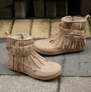 Détail de bottines à franges en daim beige avec sangle à clous et coutures blanches