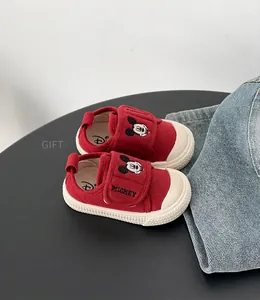 Dettaglio di scarpe di tela rosse per neonati con ricamo Mickey Mouse e suola bianca morbida