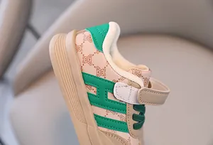 Détail d'une chaussure pour bébé avec logo H vert et motif monogramme ours en peluche.