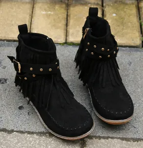 Détail de bottines en daim noir avec franges et boucle de ceinture à rivets
