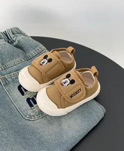 Primo piano scarpe in tela marroni per neonati con ricamo Topolino e chiusure in velcro.