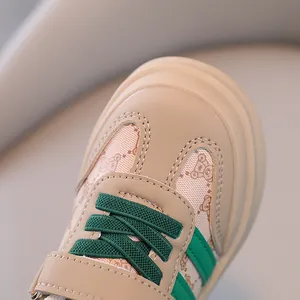 Gros plan d'une basket pour bébé beige avec lacets verts et motif d'ours