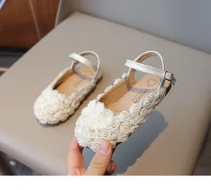Detail of cream white girls' sandals with delicate 3D fabric flower decorations