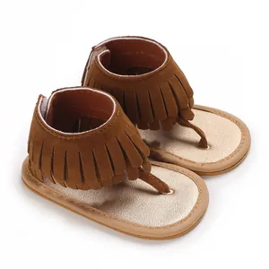 Close-up detail of brown suede tassel baby sandals with gold metallic sole and straps