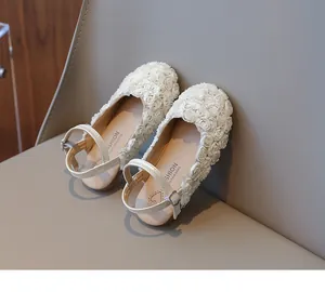 Detail of girls' closed-toe sandals with elegant 3D white floral patterns on a neutral background.