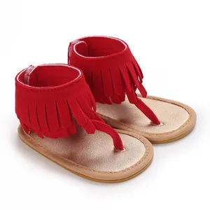 Detail of red infant thong sandals with stylish fringe ankle straps and metallic sole.