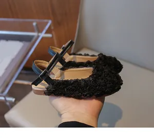 Detailed close-up of girls' black sandals featuring 3D floral textures and ankle strap.