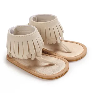 Detailed macro view of beige infant fringe thong sandals with soft gold metallic footbed