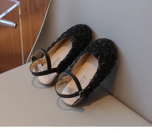 Close-up of black flower-textured girl dress shoes with ankle strap