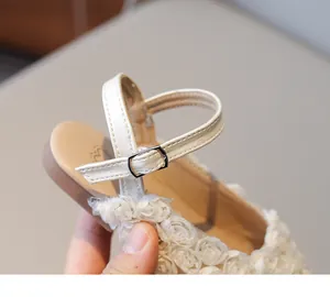 Close-up detail of girl's white flower sandals featuring an adjustable metal buckle