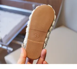 Detailed view of the anti-slip brown rubber sole of a girl's white floral sandal shoe