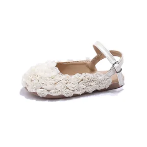 Close-up of elegant white girls' sandals featuring delicate fabric rose embellishments.