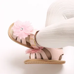 Detalle de sandalias rosas para bebé con diseño de flor decorativa grande y hebilla.