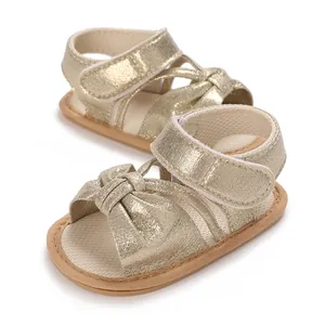 Close-up of gold glitter baby sandals with bow and velcro strap for girls