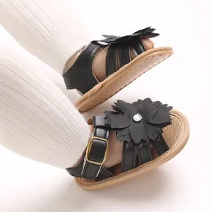 Primer plano de sandalias negras para bebé con diseño de flores y calcetines blancos