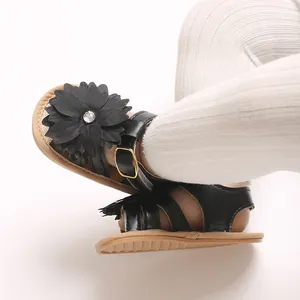 Primer plano de sandalias negras para bebé con gran flor decorativa y hebilla dorada