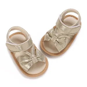 High quality detail shot of baby girl gold glitter sandals with decorative bow and soft sole.