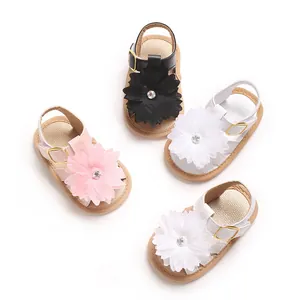 Detalle de sandalias para niñas con grandes flores decorativas en rosa, blanco y negro.