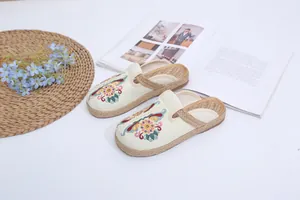 Detailed overhead view of ethnic floral embroidered slippers with braided rope soles