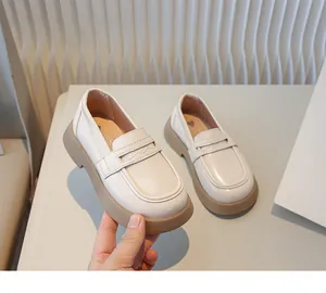 Detailweergave van crèmekleurige Britse loafers voor kinderen met dikke bruine zool