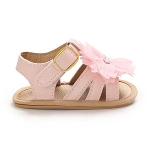 Detalle de sandalias rosas para bebé con adorno de flor grande y cierre de velcro cómodo.
