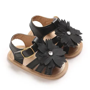 Detalle de sandalias negras para bebé niña con flor decorativa grande y pedrería